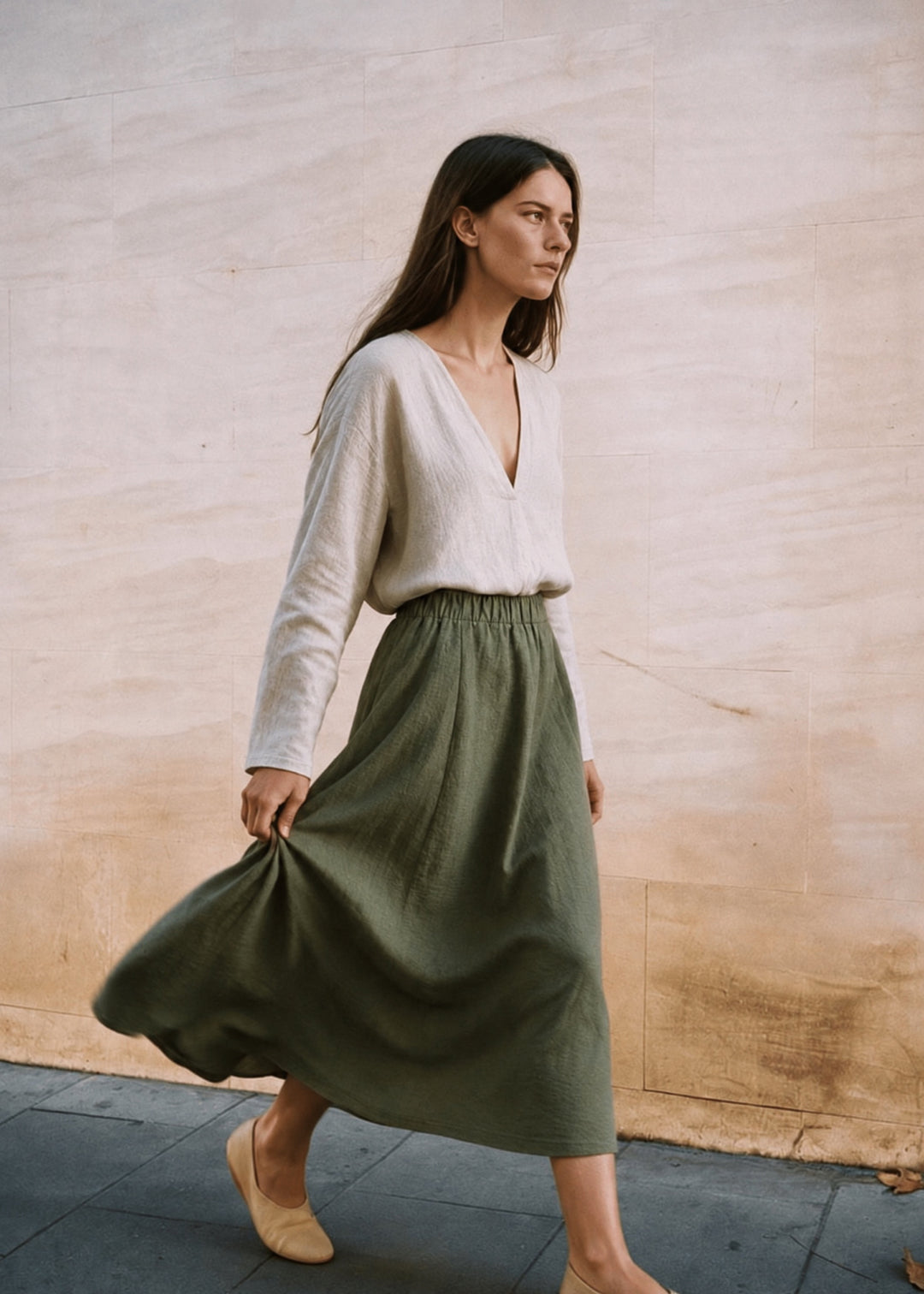 Woman walking in the olive A-Line Paneled Skirt, the midi hem swinging.