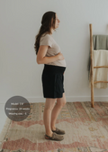 Pregnant model in black linen smocked shorts, side view.