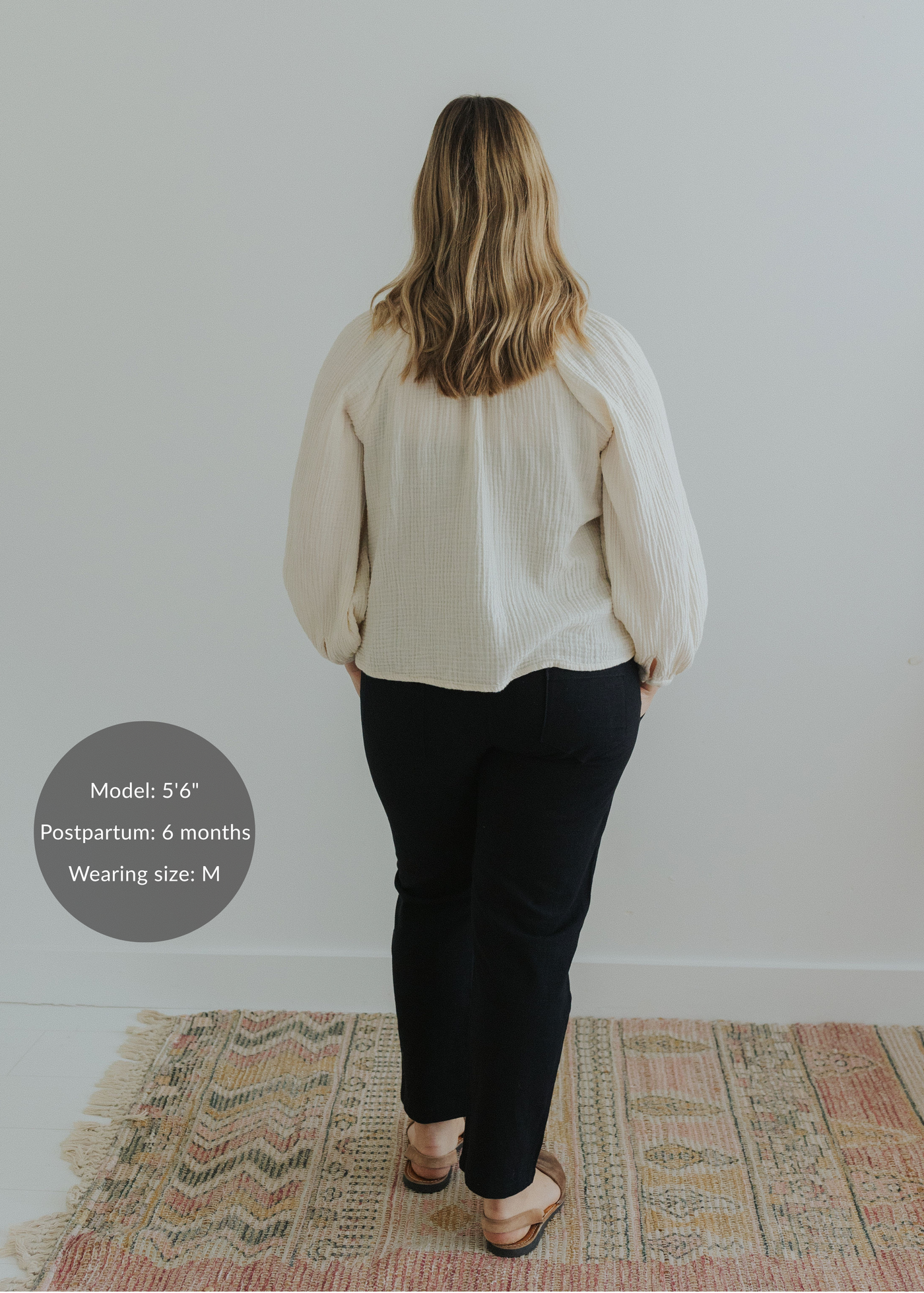 Woman from behind wearing black smocked linen pants and a cream top, with brown sandals.