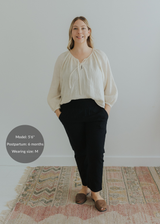Woman in black smocked linen pants and an off-white blouse, hands in pockets.