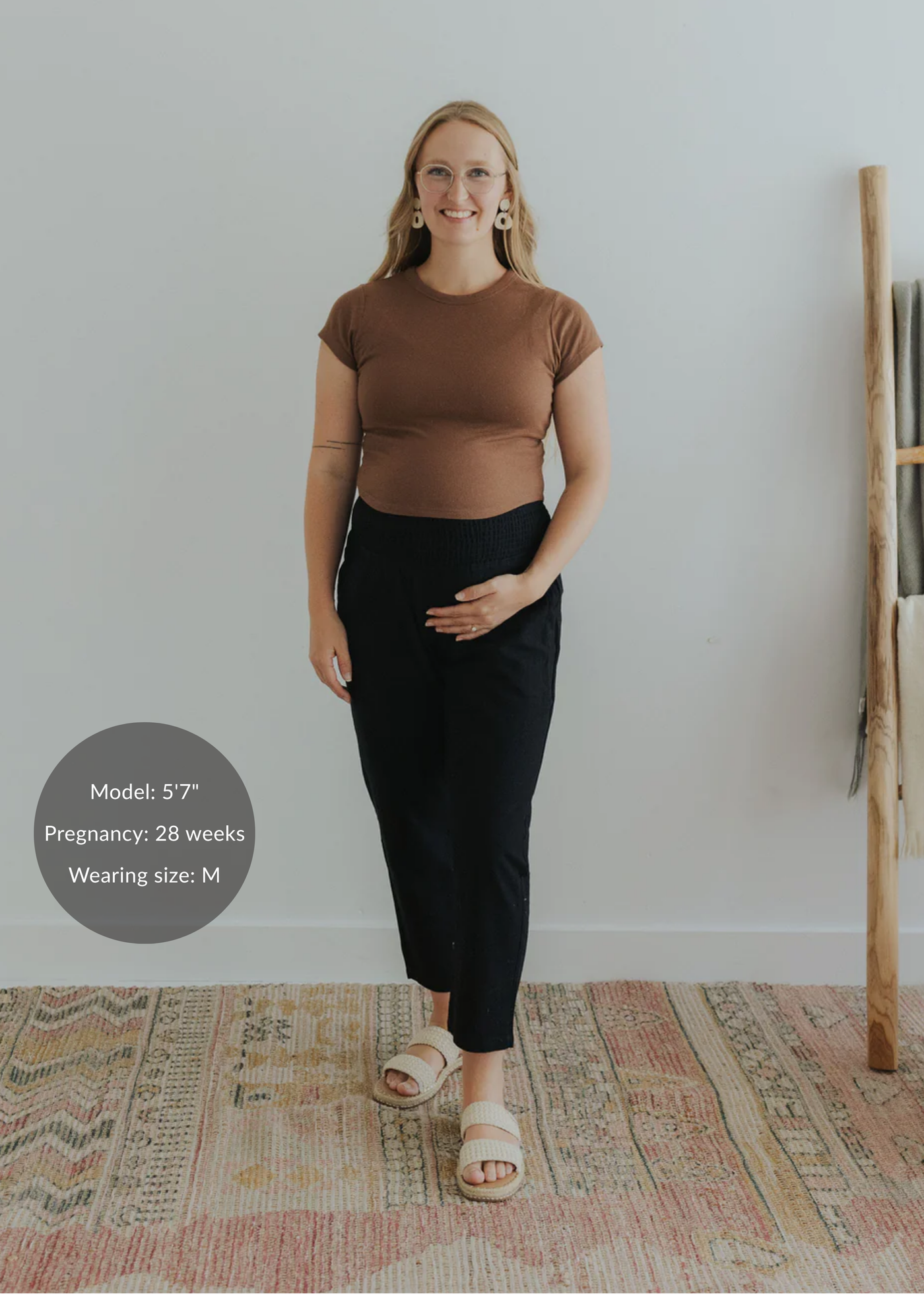 Pregnant model in black smocked linen maternity pants, brown top, and cream sandals.
