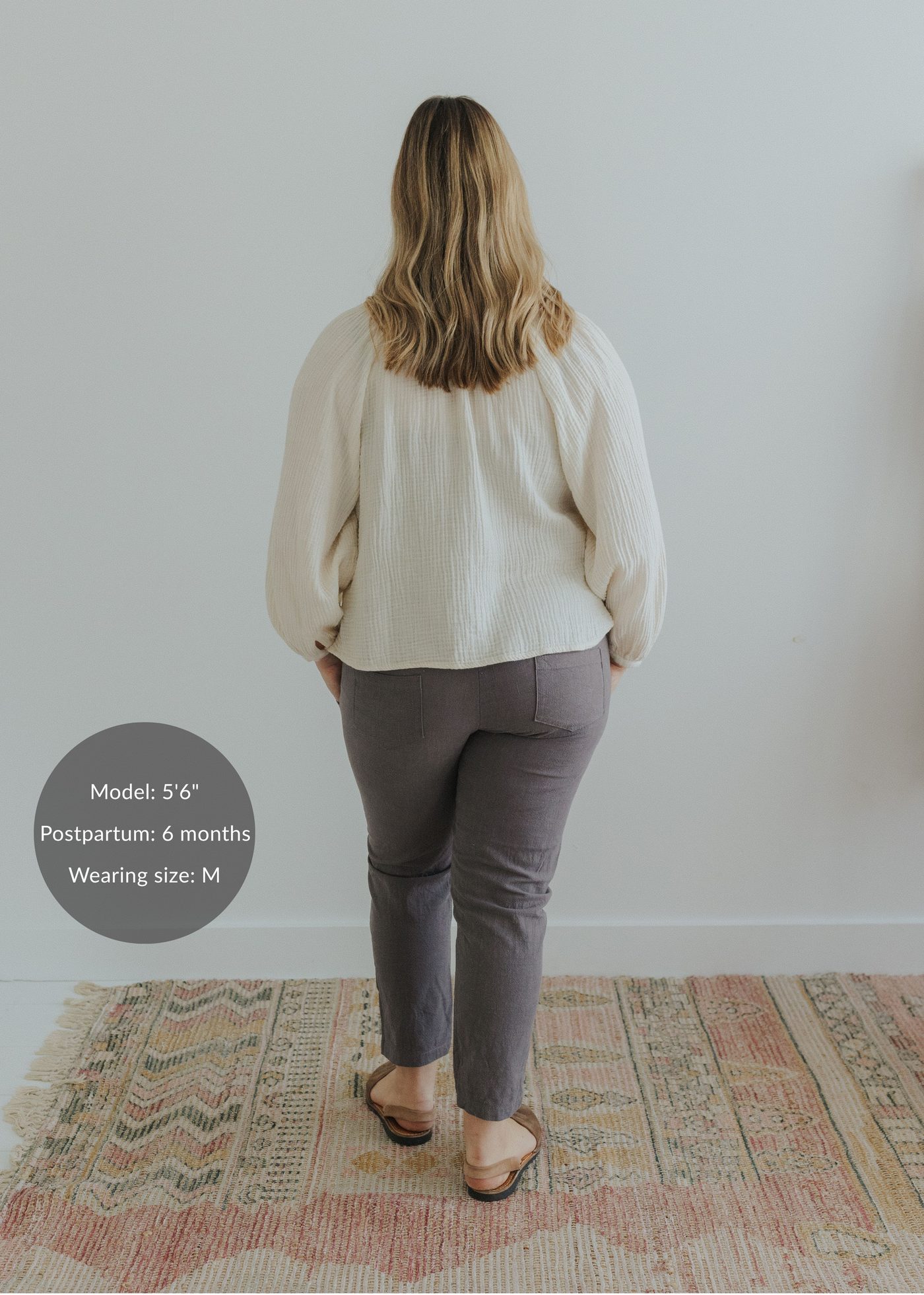 Woman from behind wearing charcoal smocked linen pants and an off-white blouse.