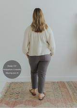 Woman from behind wearing charcoal smocked linen pants and an off-white blouse.