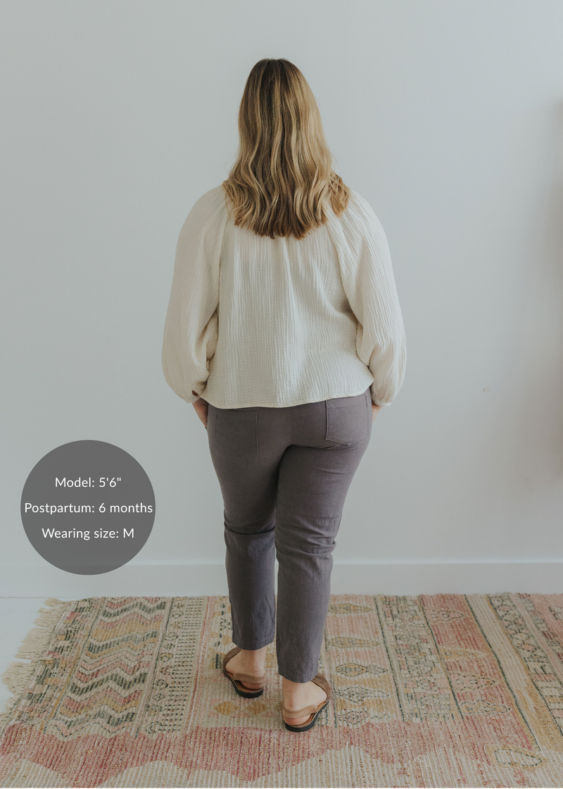 Woman from behind wearing charcoal smocked linen pants and an off-white blouse.