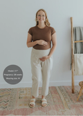 Pregnant woman in smocked waist natural linen pants, brown top, and sandals.
