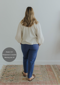 Woman from behind wearing Everyday Transitional Smocked Linen Pants in blue with a cream blouse.