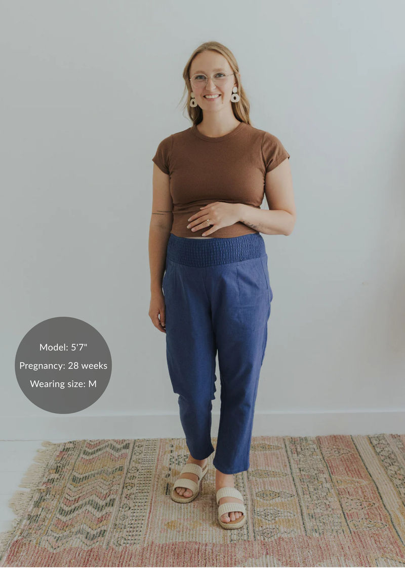 Smiling pregnant model in blue smocked linen maternity pants and brown top.