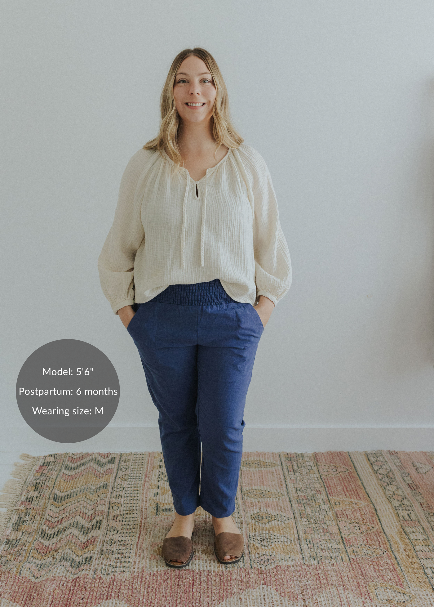 Woman in navy smocked linen pants with pockets and an off-white blouse.
