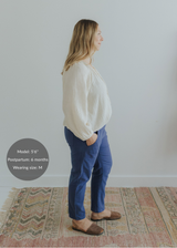 Woman in blue smocked linen pants with pockets and an off-white blouse, side profile.