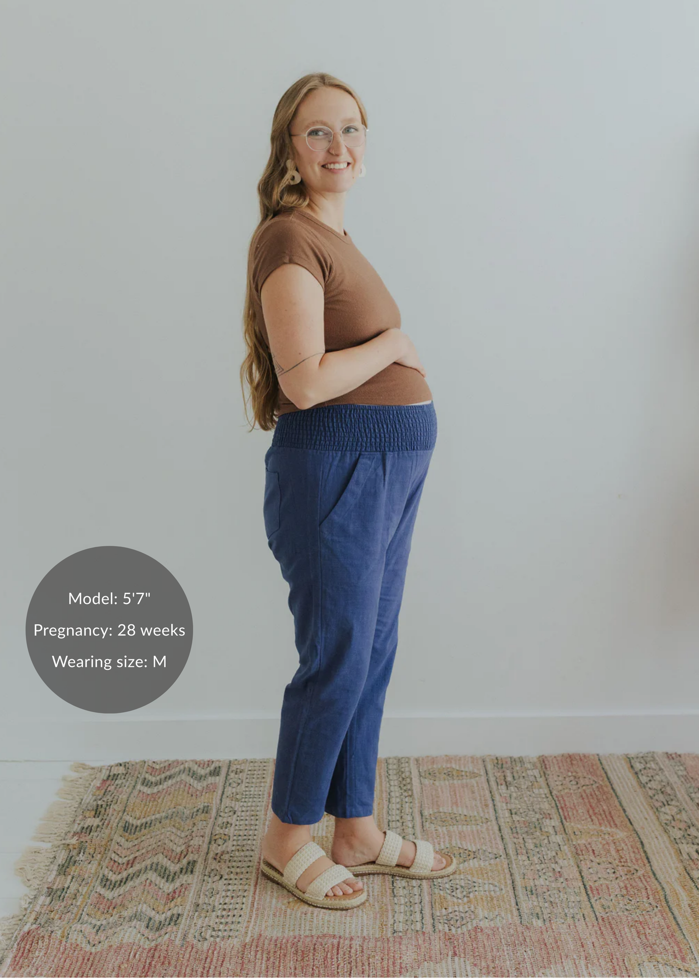 Pregnant woman in blue smocked linen maternity pants with pockets and a brown top.