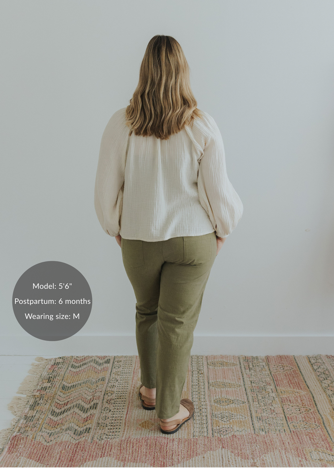 Woman from behind wearing olive green smocked linen pants and an off-white blouse.
