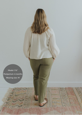 Woman from behind wearing olive green smocked linen pants and an off-white blouse.