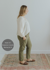Woman in olive green smocked linen pants with pockets, paired with a cream top and brown flats.