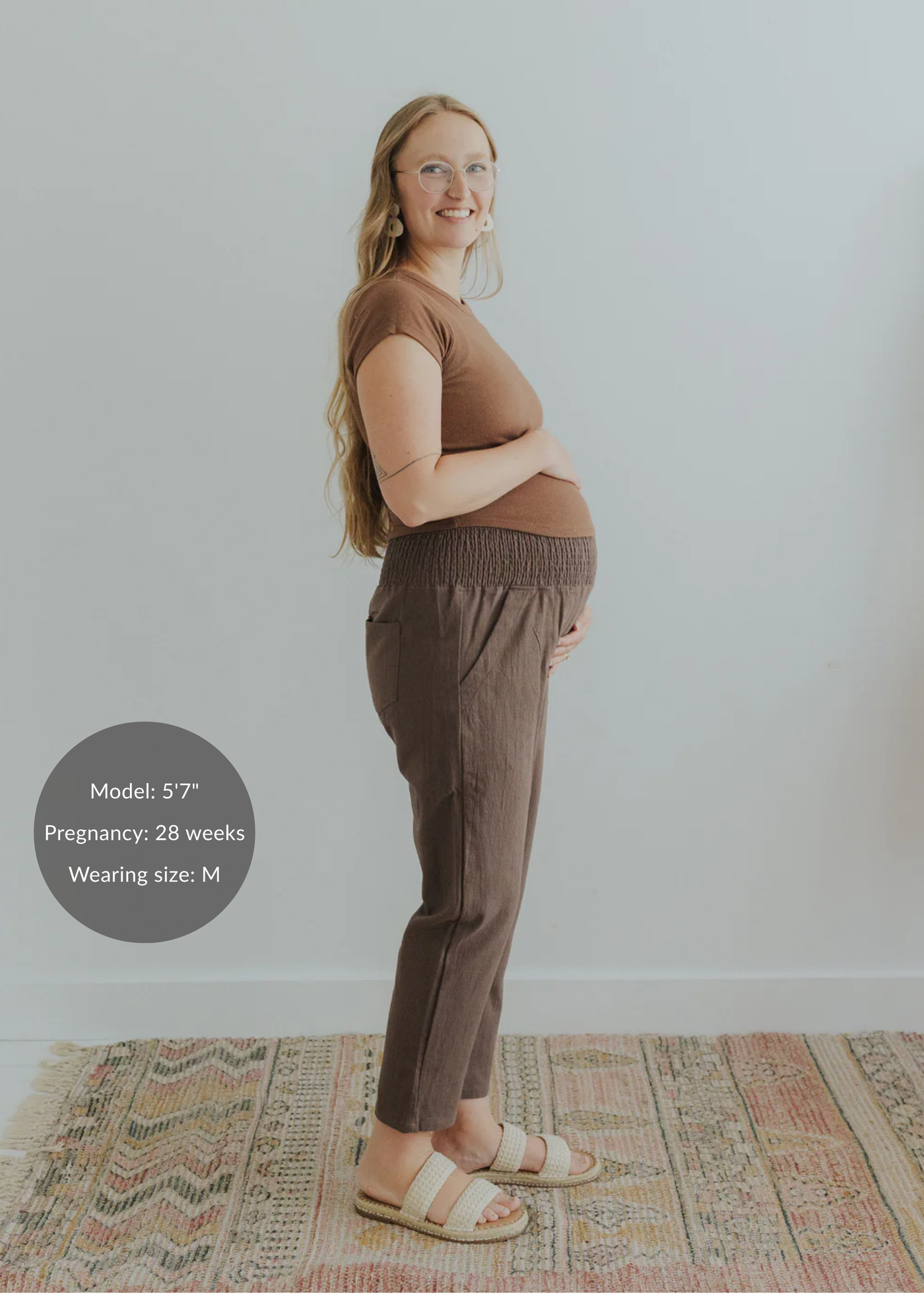 Pregnant woman in brown smocked linen maternity pants with pockets and a matching top.