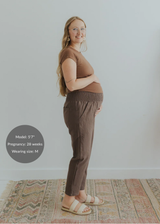 Pregnant woman in brown smocked linen maternity pants with pockets and a matching top.