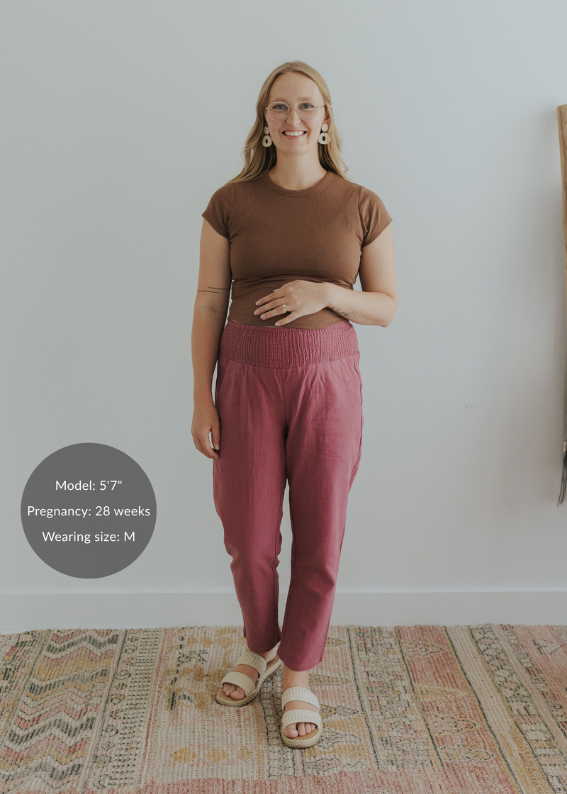 Pregnant woman in smocked rose linen pants, brown top, and sandals.