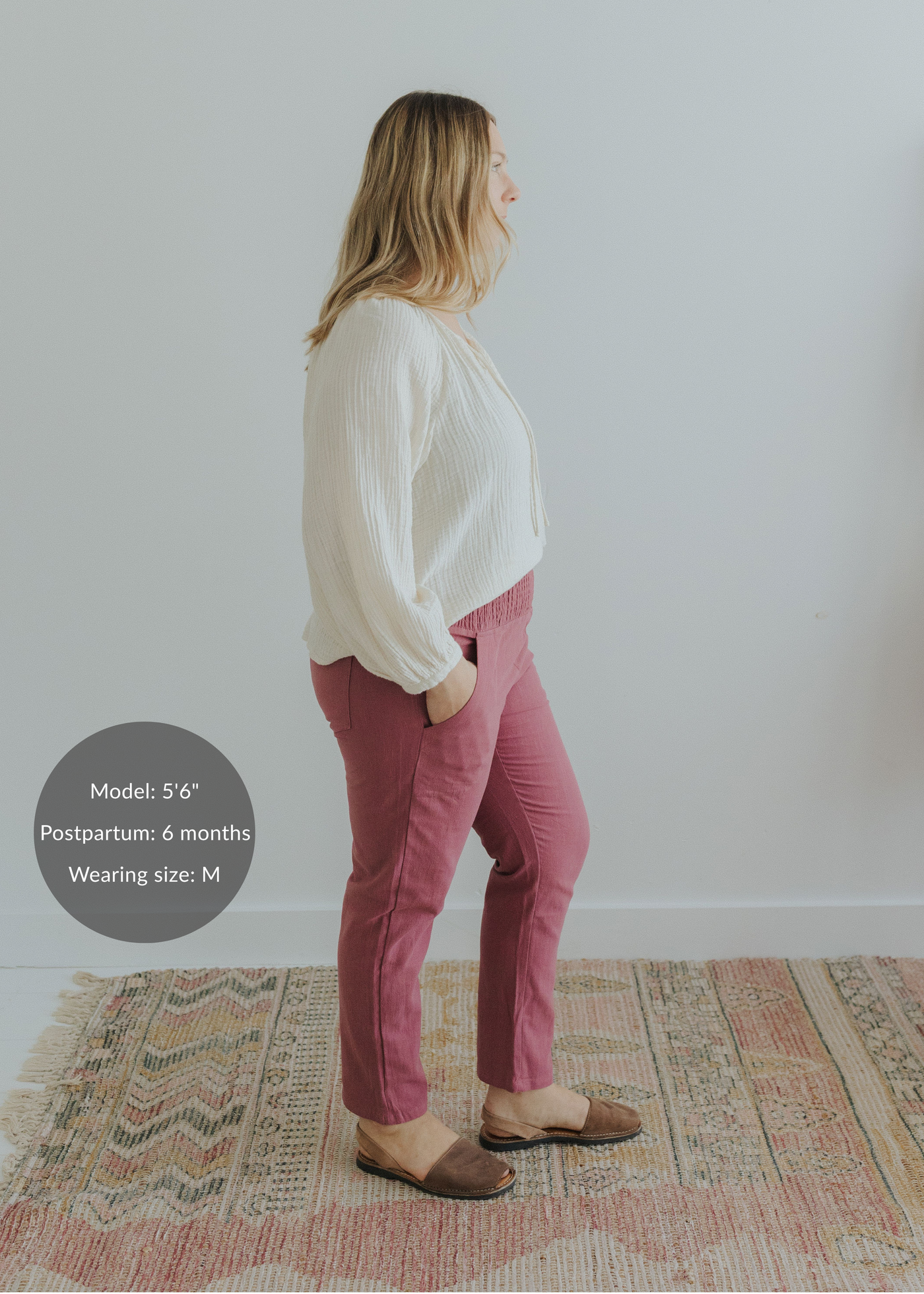 Woman in rose smocked linen maternity pants with pockets and an off-white blouse.