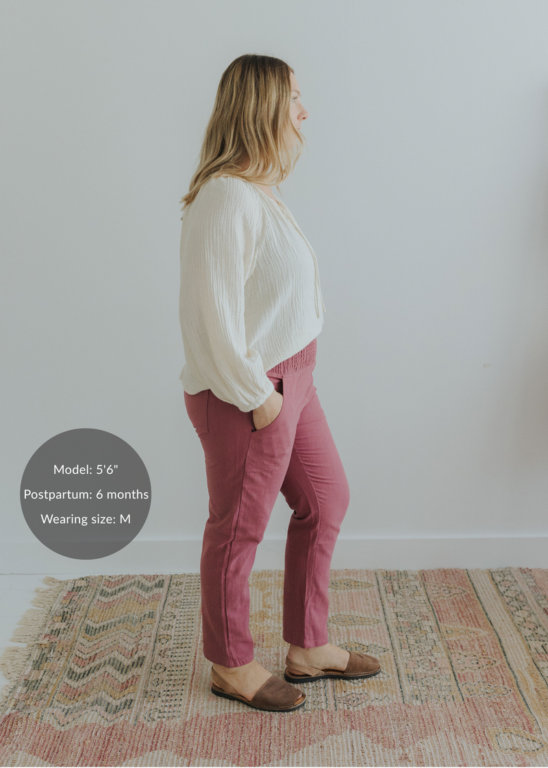 Woman in rose smocked linen maternity pants with pockets and an off-white blouse.