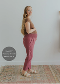 Pregnant woman in a brown top and smocked rose linen maternity pants with pockets.