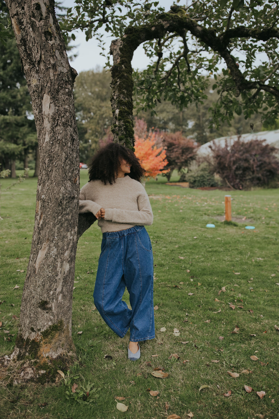 Woman leaning on an apple tree in the Indigo Balloon Jean Pant