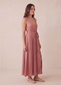 Woman in a rose pink linen-cotton blend adjustable pleated wrap maxi dress with a waist tie.