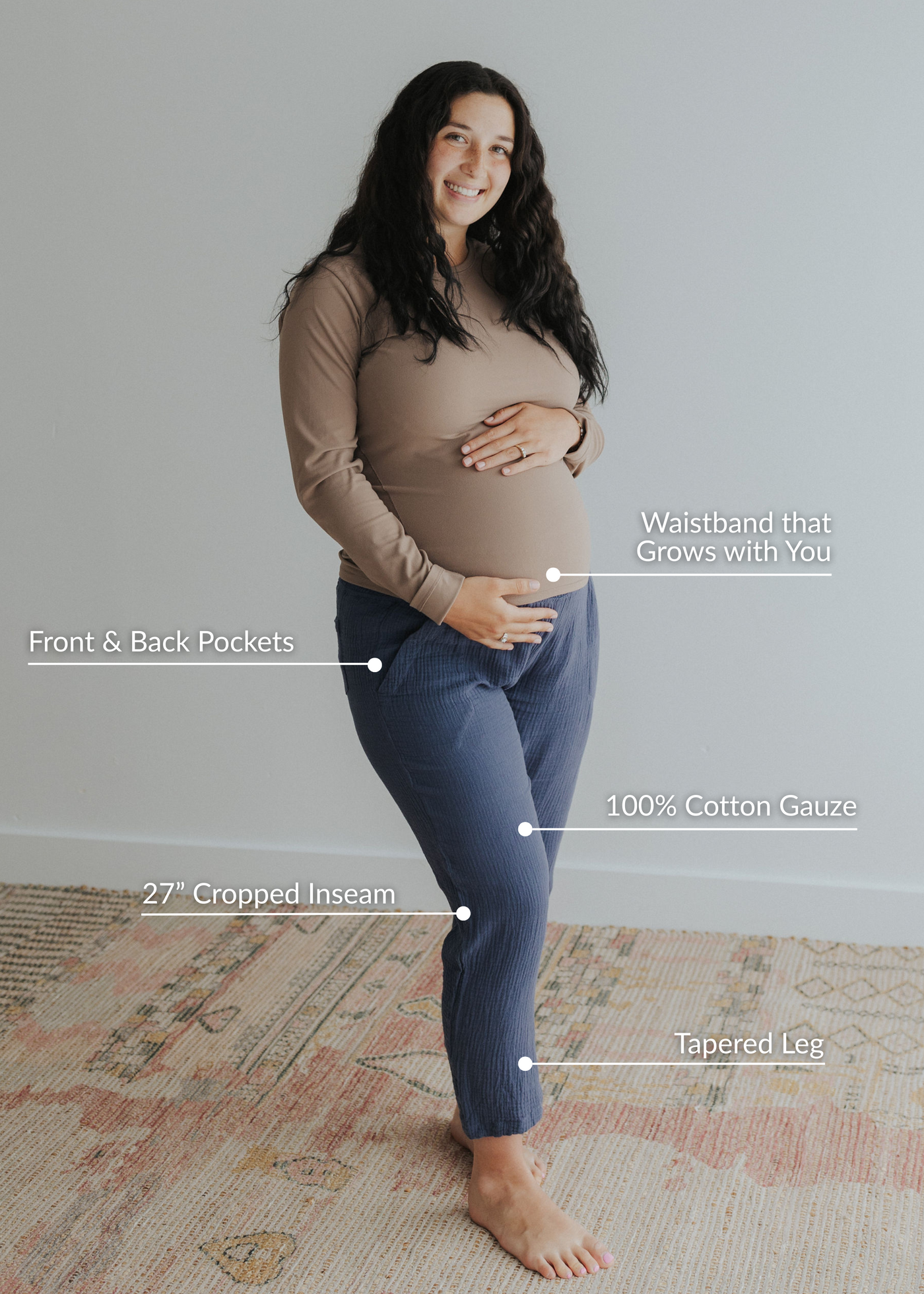 Smiling pregnant woman wearing Everyday Breeze Pant in blue cotton gauze with elastic waistband, pockets, and tapered cropped leg.