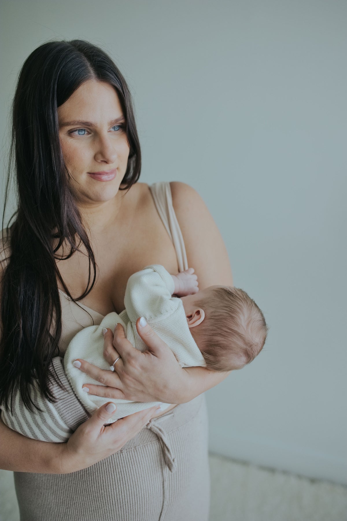 Woman holding her baby in the Sand Crossover Sleep Bra, close front view