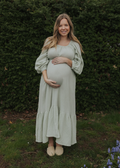 Pregnant woman in a seafoam green cotton gauze maxi dress with balloon sleeves, smocked waist, and ruffle skirt.