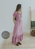 Woman in a mauve organic cotton gauze maxi dress with smocked elastic waist, scoop neck, and short sleeves.