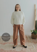 Woman in Everyday Barrel Pant, a rust-colored linen/cotton blend, with a cream sweater.