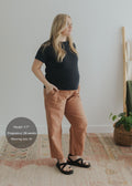 Pregnant woman in Everyday Barrel Pant, rust-colored linen/cotton blend, with deep pockets and barrel legs.