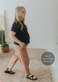 Pregnant woman in a black tee and Everyday Barrel Pant in rust linen/cotton, size M.