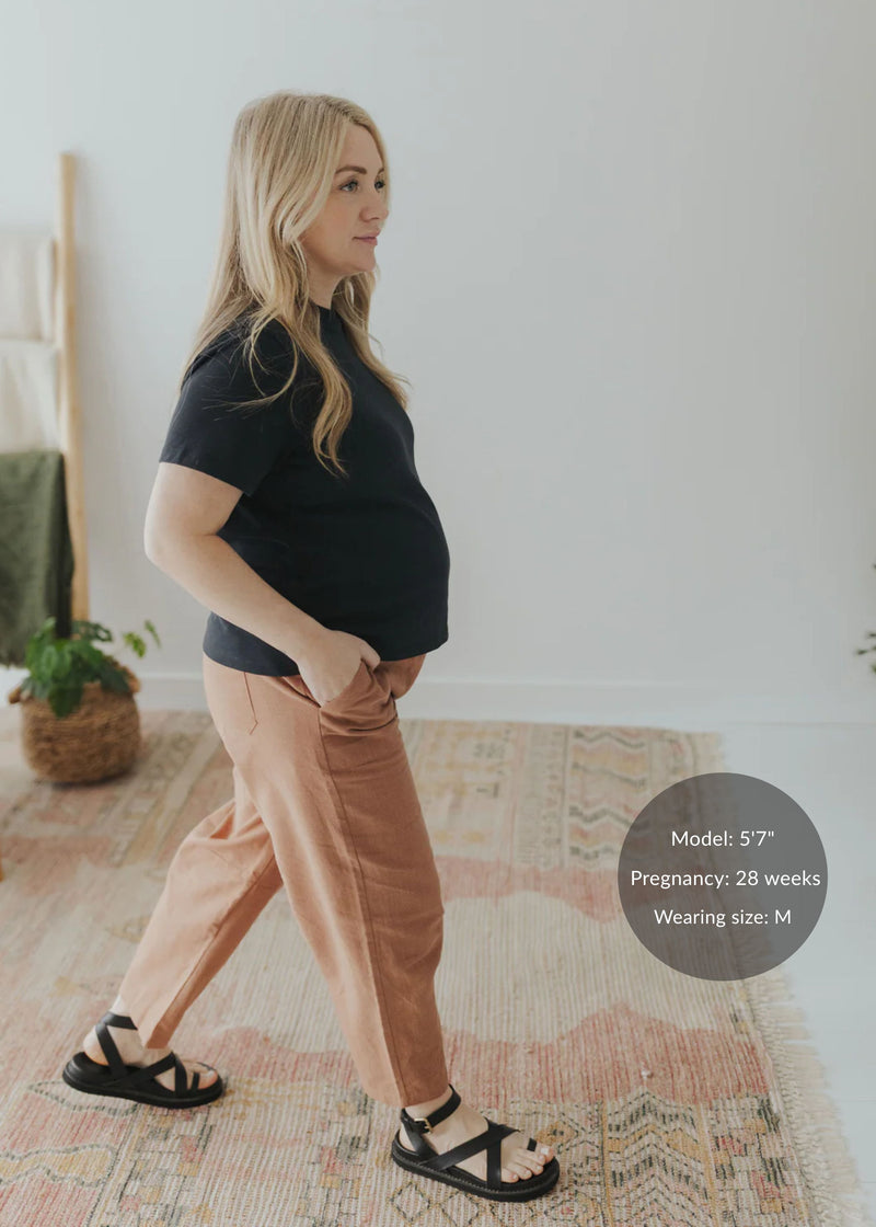 Pregnant woman in a black tee and Everyday Barrel Pant in rust linen/cotton, size M.