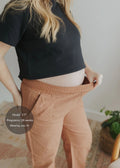 Pregnant model in rust linen/cotton Everyday Barrel Pant, showing stretchy waistband and deep pockets.