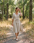 Woman wearing the Faye Dress in Natural sandwashed linen on a wooded trail