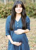 Pregnant woman in a navy blue linen Faye Dress with a V-neck, front buttons, and a-line silhouette.