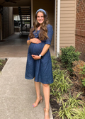 Pregnant woman in a navy linen Faye Dress with front buttons, v-neck, and a-line silhouette.