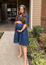 Pregnant woman in a navy linen Faye Dress with front buttons, v-neck, and a-line silhouette.