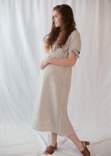 Pregnant woman in a natural linen-cotton Florence Midi Dress with ruched waist and tie sleeves.