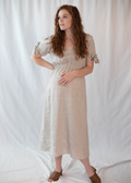 Pregnant woman in a natural linen-cotton Florence Midi Dress with tied sleeves and a relaxed silhouette.