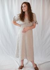 Pregnant woman in a natural linen-cotton Florence Midi Dress with tied sleeves and a relaxed silhouette.