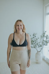 Smiling woman in the Ebony Front Clasp Nursing Bra with oatmeal knit shorts, front view