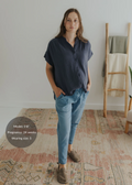 Woman in a navy cotton gauze button-down top and light blue pants, hands in pockets.