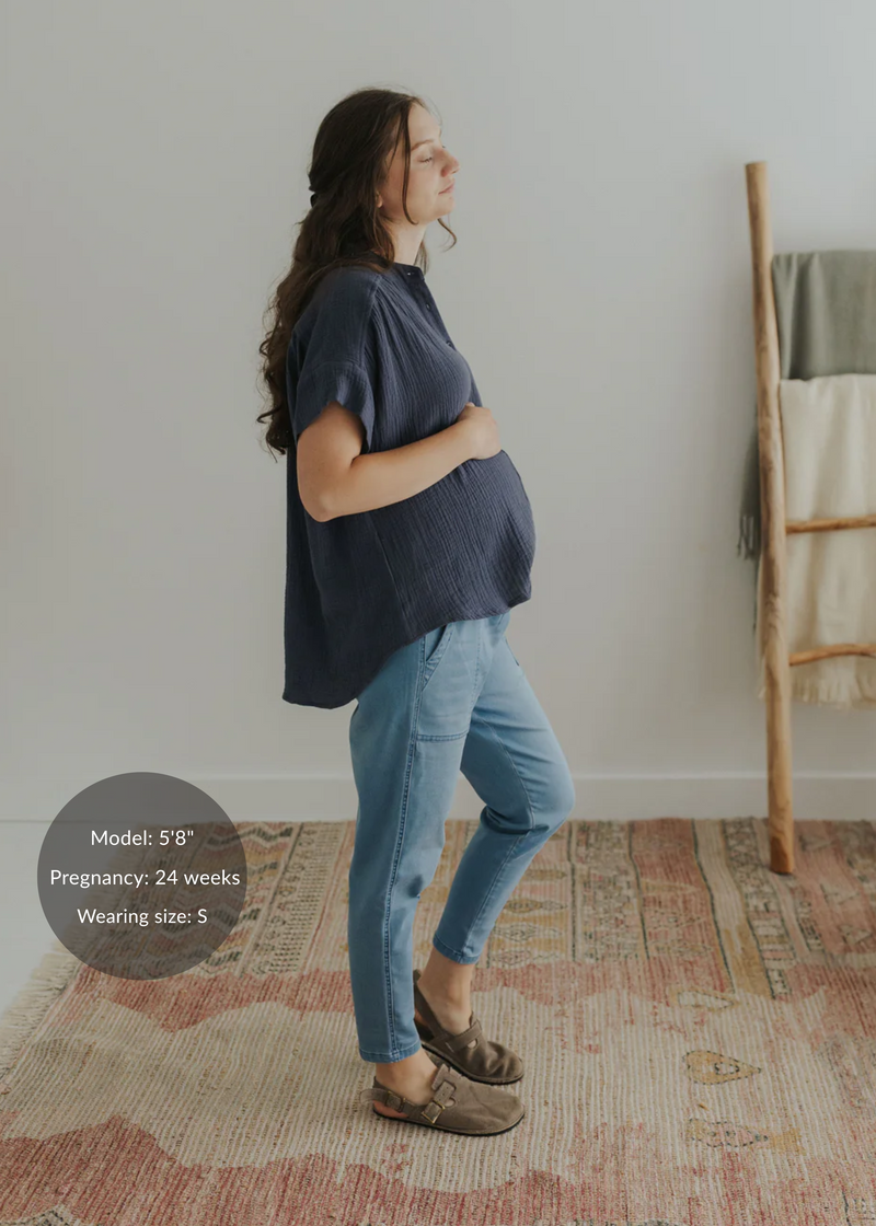 Pregnant woman in a navy cotton gauze oversized button-down top and light blue jeans.