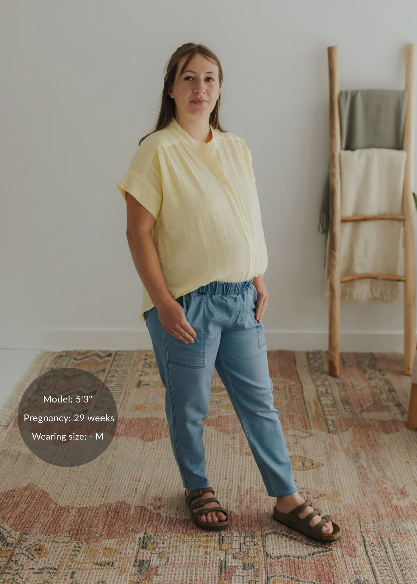Pregnant woman in a light yellow cotton gauze button-down top and blue pants.