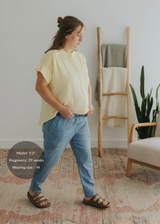Woman in a loose-fitting yellow cotton gauze button-down top, light blue pants, and brown sandals.