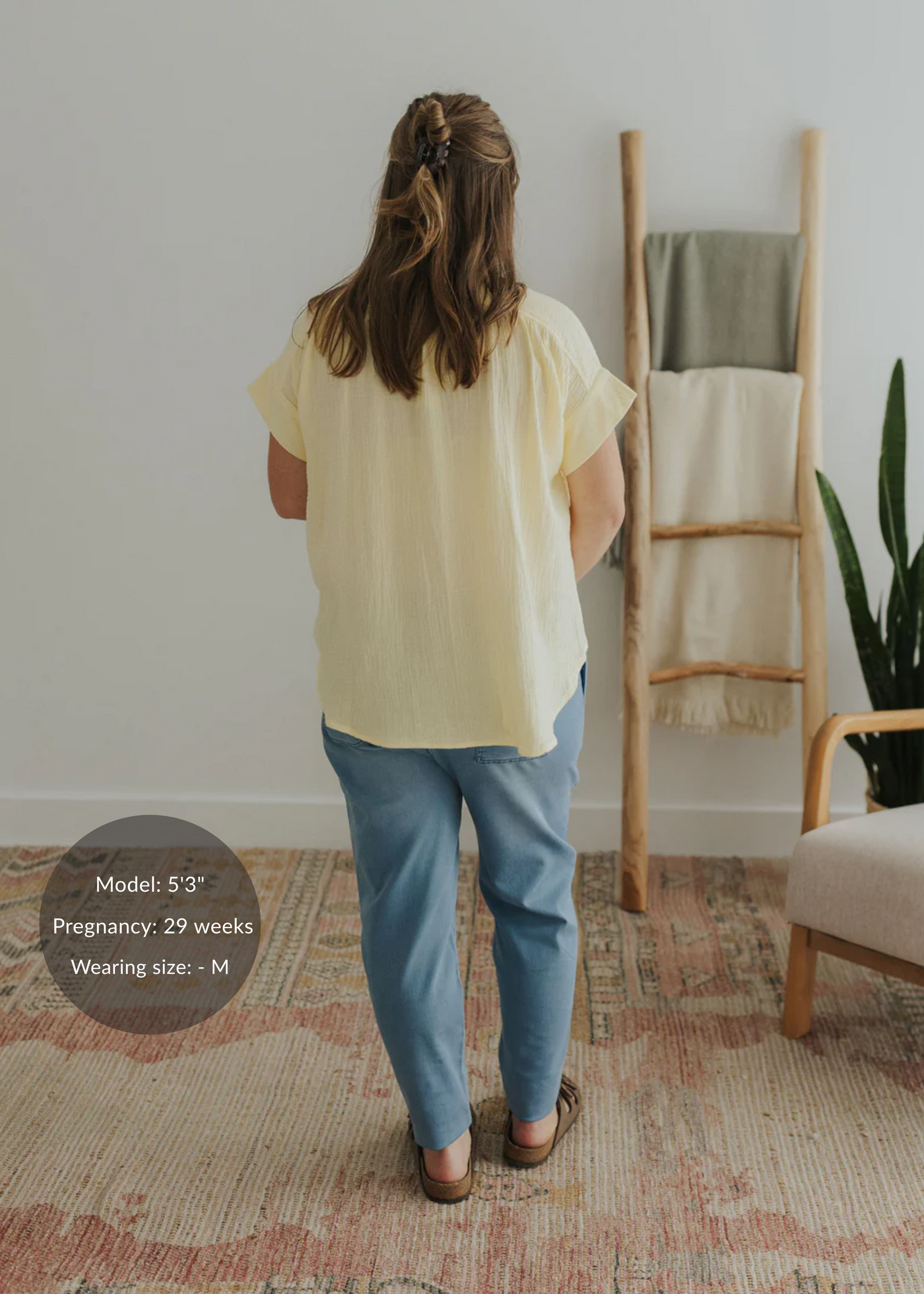 Woman from behind wearing an oversized light yellow cotton gauze button-down top and blue pants.