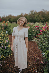 Smiling woman in the Beige Hazel Front Button Dress, front view showing the buttons and short sleeves