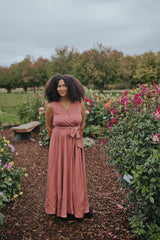 Woman in the Dusty Rose Iris Sleeveless Wrap Dress, front view, full length in a dahlia garden