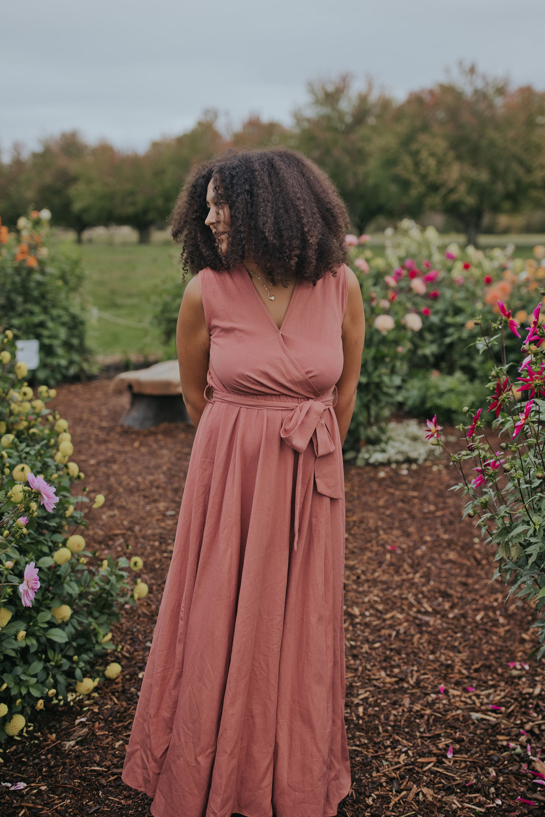 Woman in the Dusty Rose Iris Sleeveless Wrap Dress, closer front view of the wrap bodice and tie